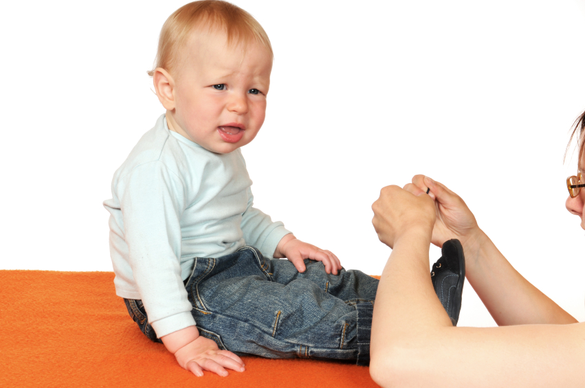 a young boy looking upset as his mom dresses him